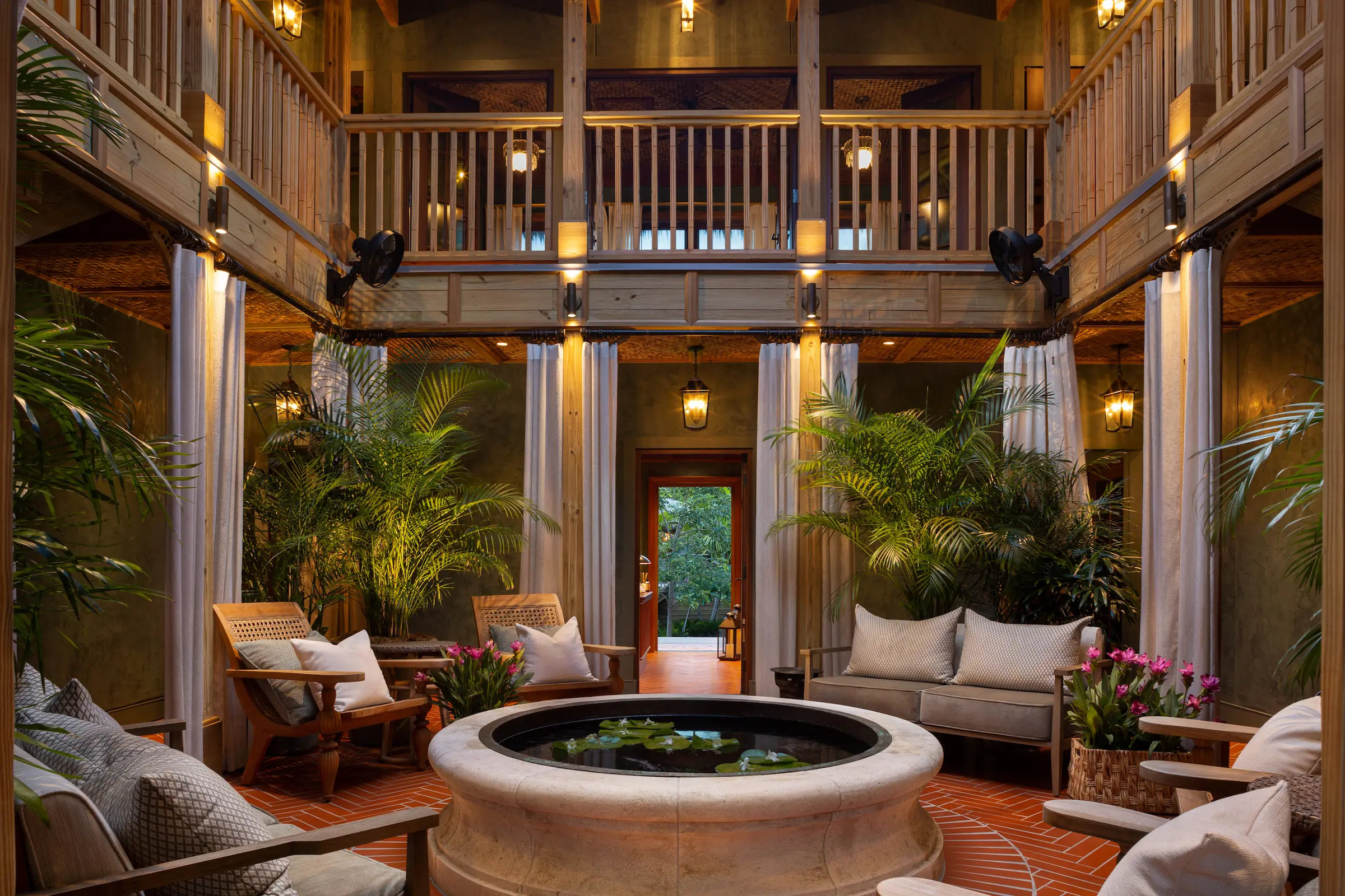 A lush, open-air courtyard with a central circular water feature in SpaTerre