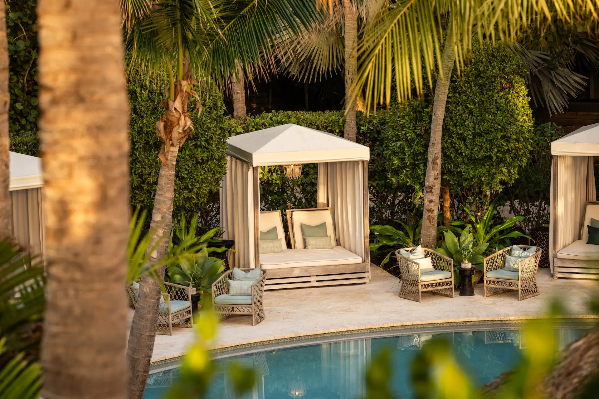 A cabana by the pool surrounded by large trees at Little Palm Island Resort