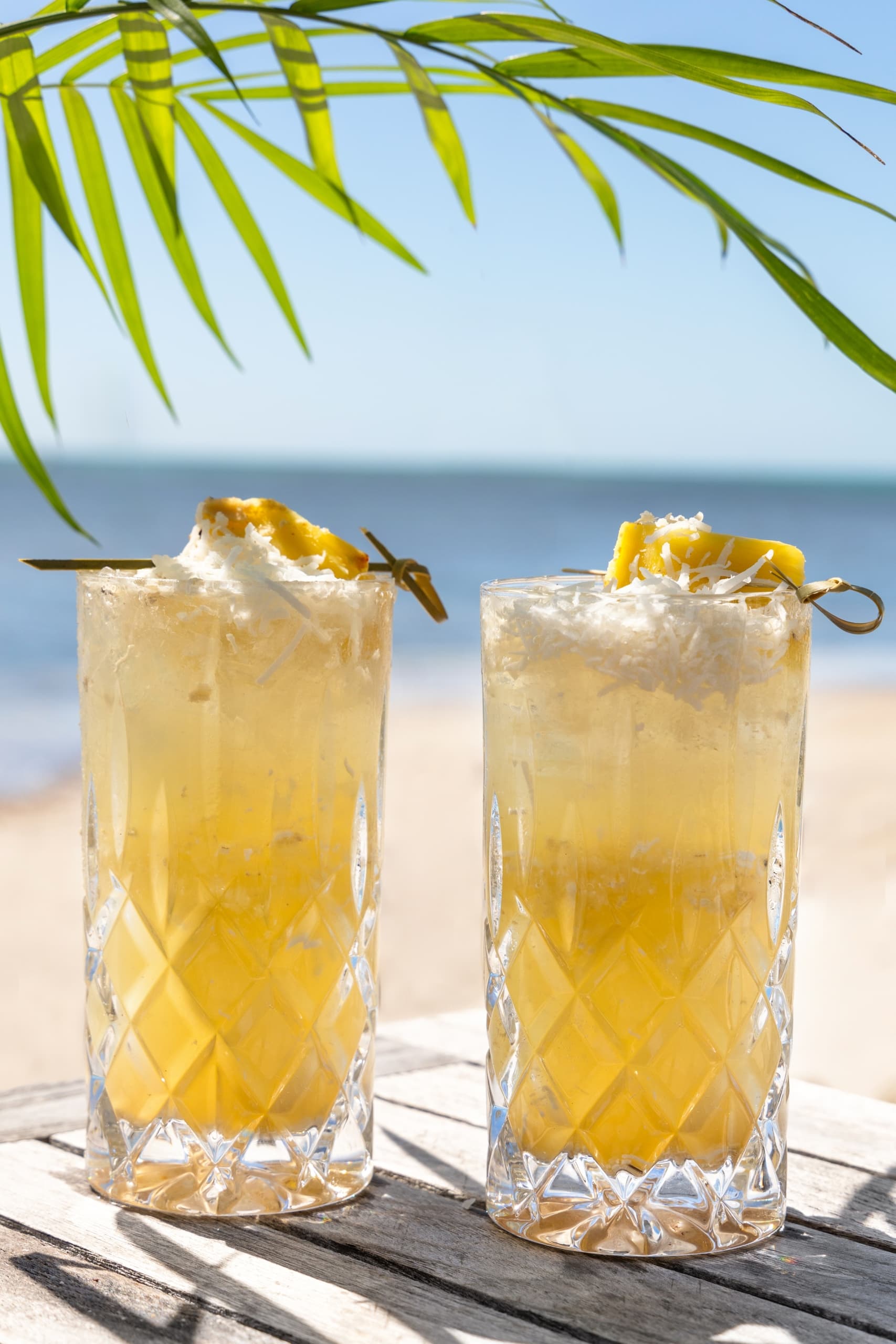 Two pineapple cocktails sitting on the beach ready to drink from the Monkey Bar