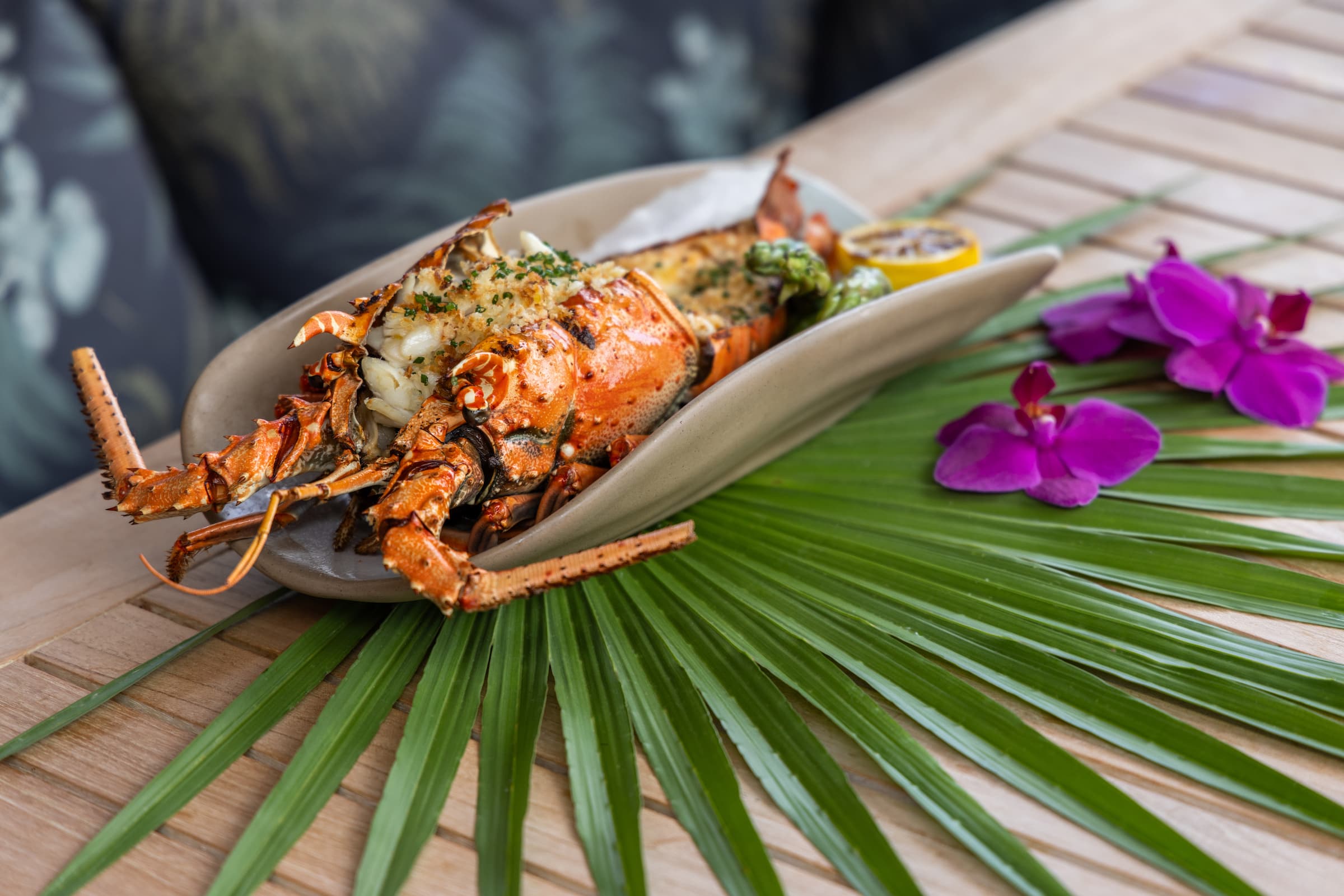 A whole cooked lobster with chive, grilled lemon, and asparagus served at Little Palm Island Resort