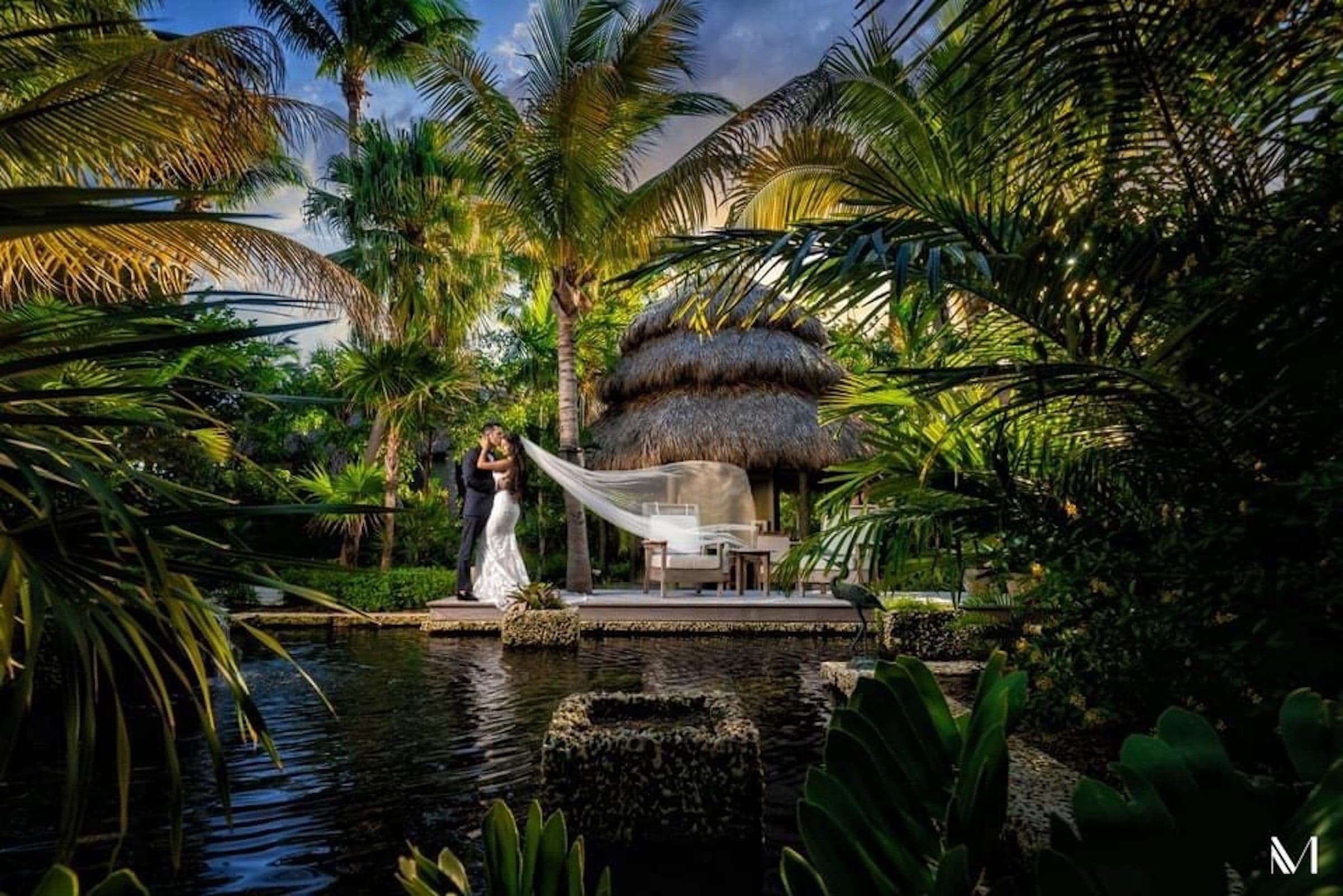 A bride and groom dancing by a lagoon-style pool at Little Palm Island Resort