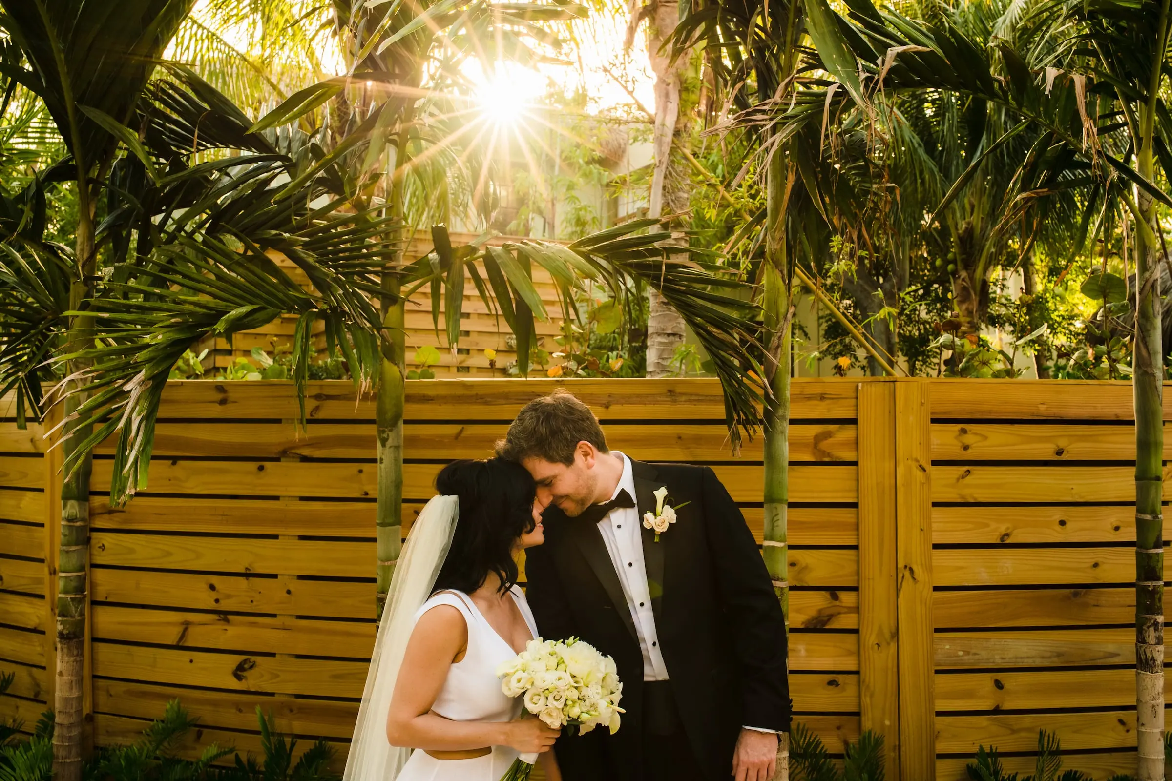 A bride and groom behind a wooden fence after their wedding at Little Palm Island Resort