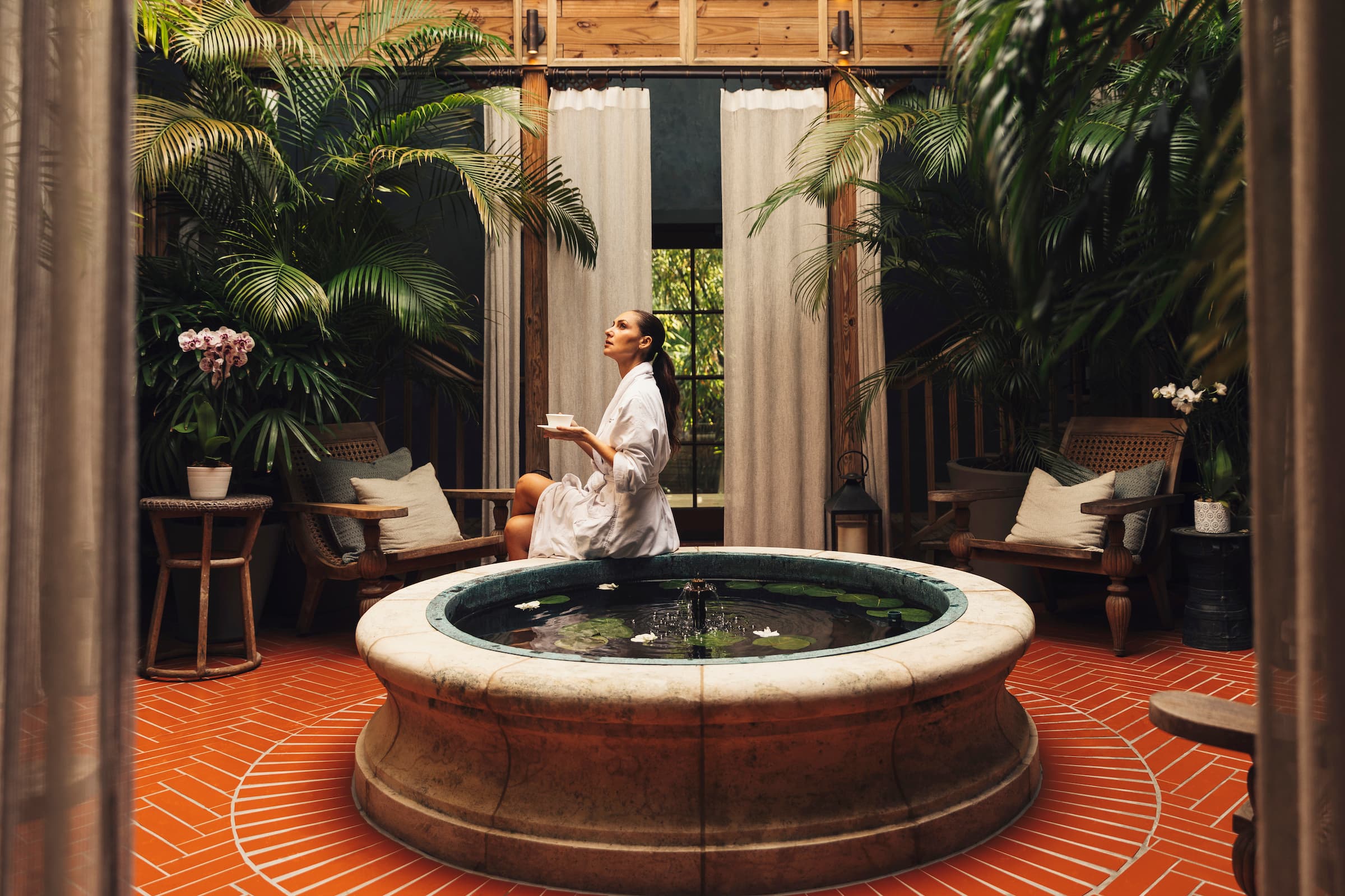 A robed woman enjoying a cup of tea sitting on a tub in SpaTerre