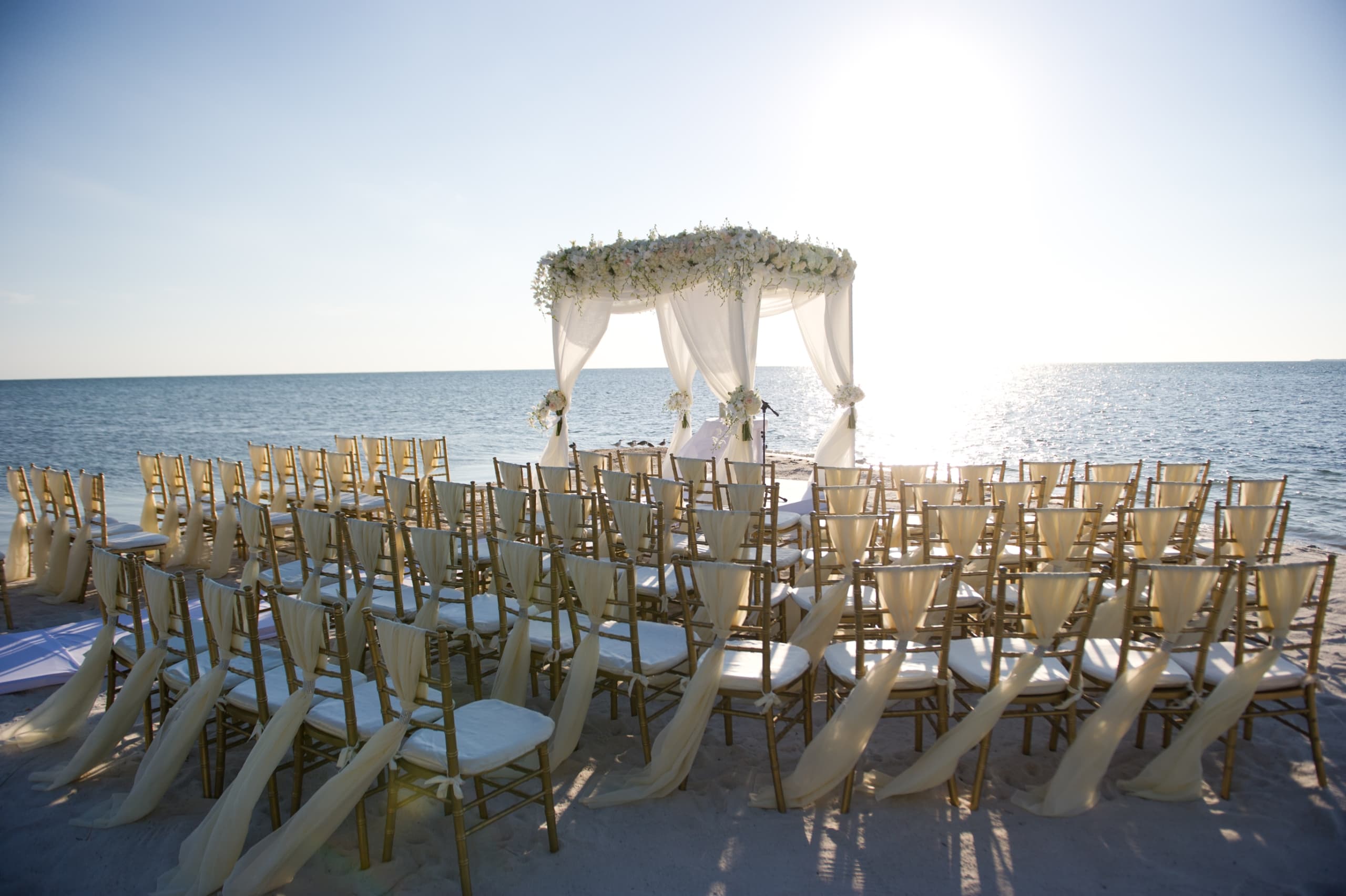 Chairs and a gazebo set up on a white sand beach for a wedding on Little Palm Island