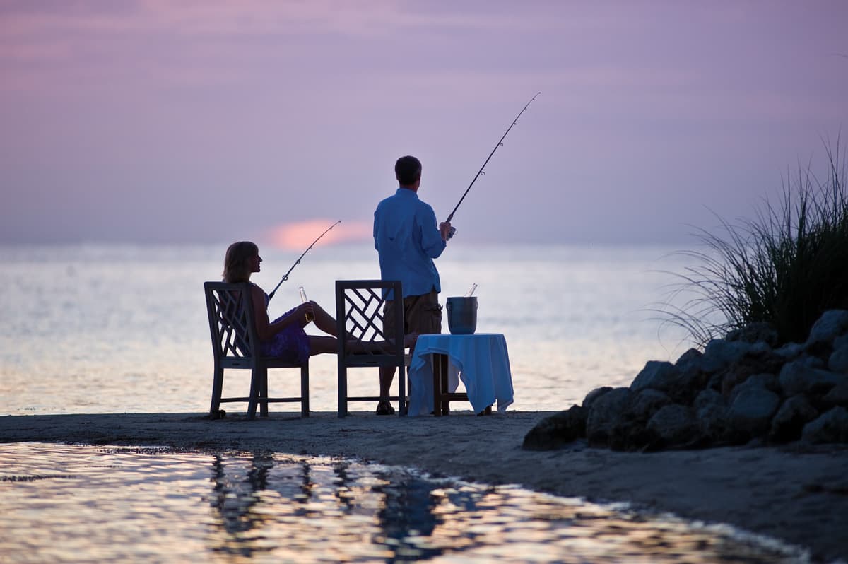A couple fishing off the beach at Little Palm Island Resort