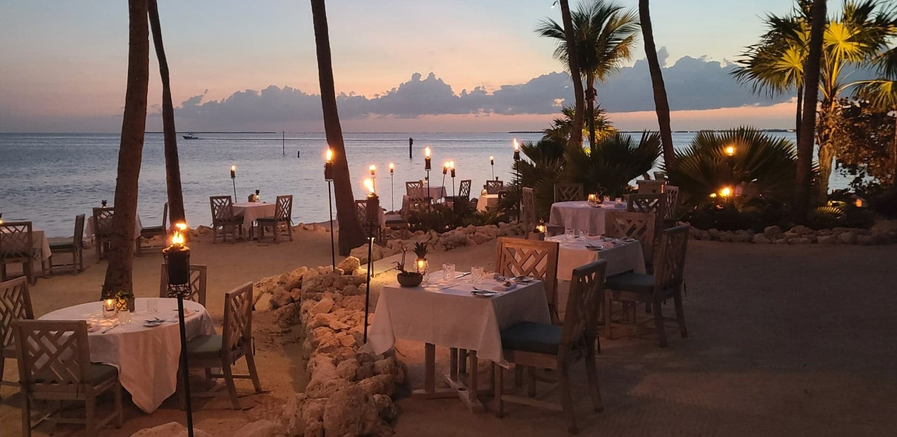 Sandbar dining on Little Palm Island with tiki torches lit.