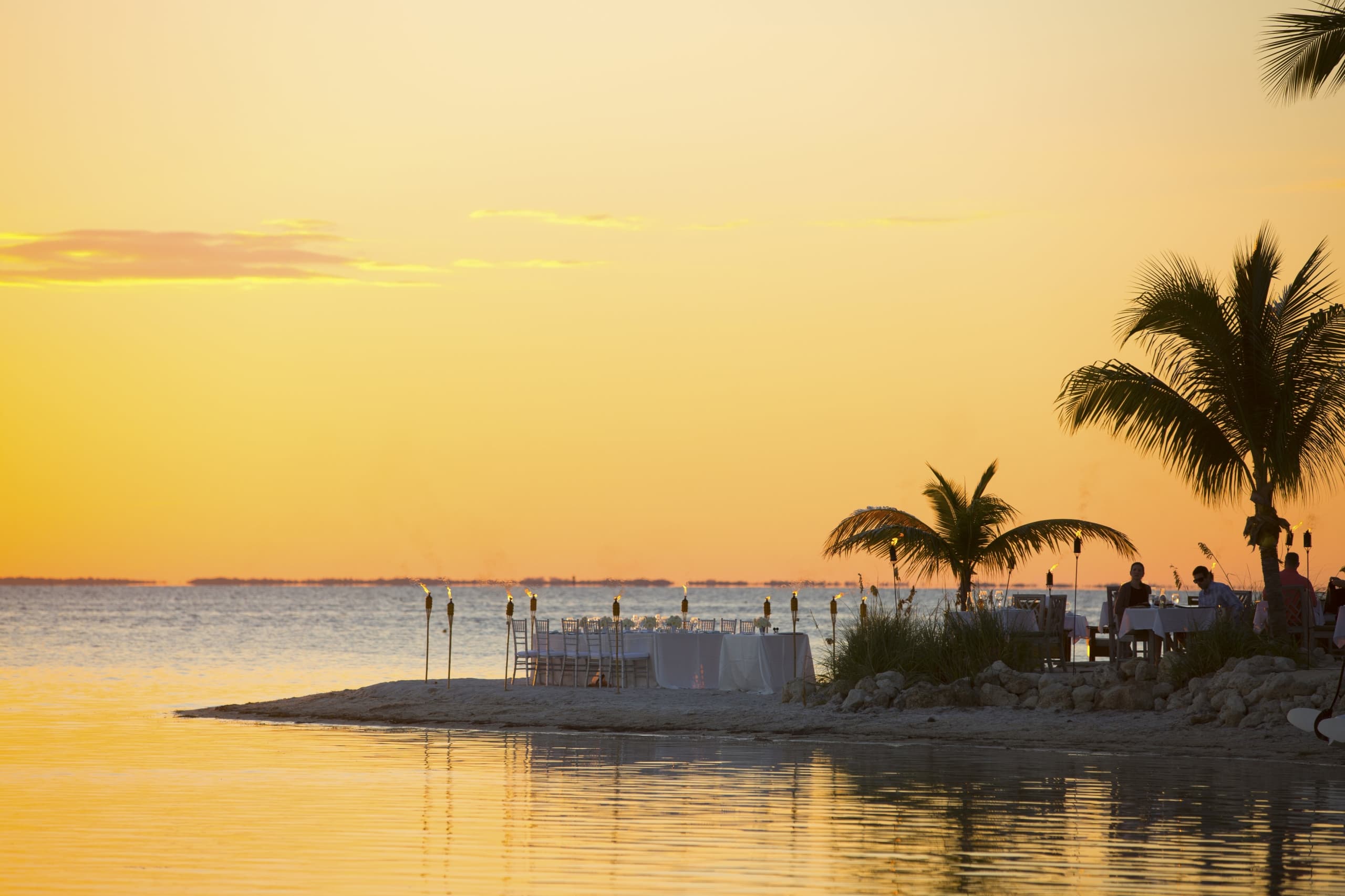 An outdoor, oceanfront wedding reception at sunset at Little Palm Island Resort.