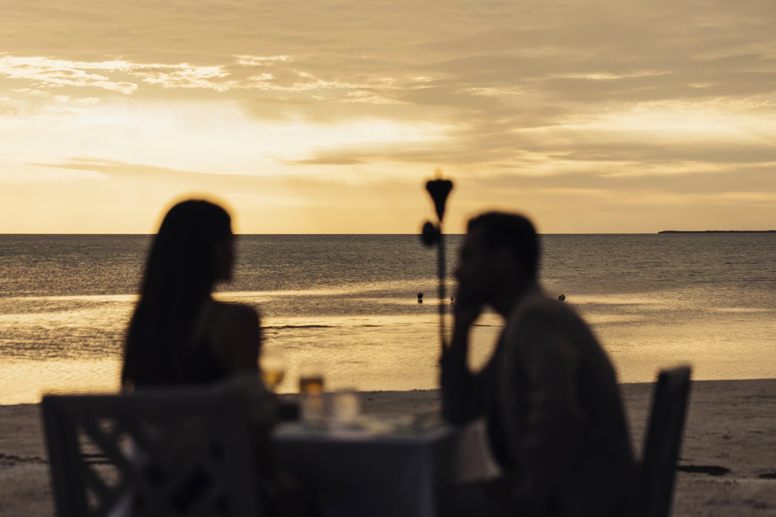 A couple dining at the beach at sunset at Little Palm Island