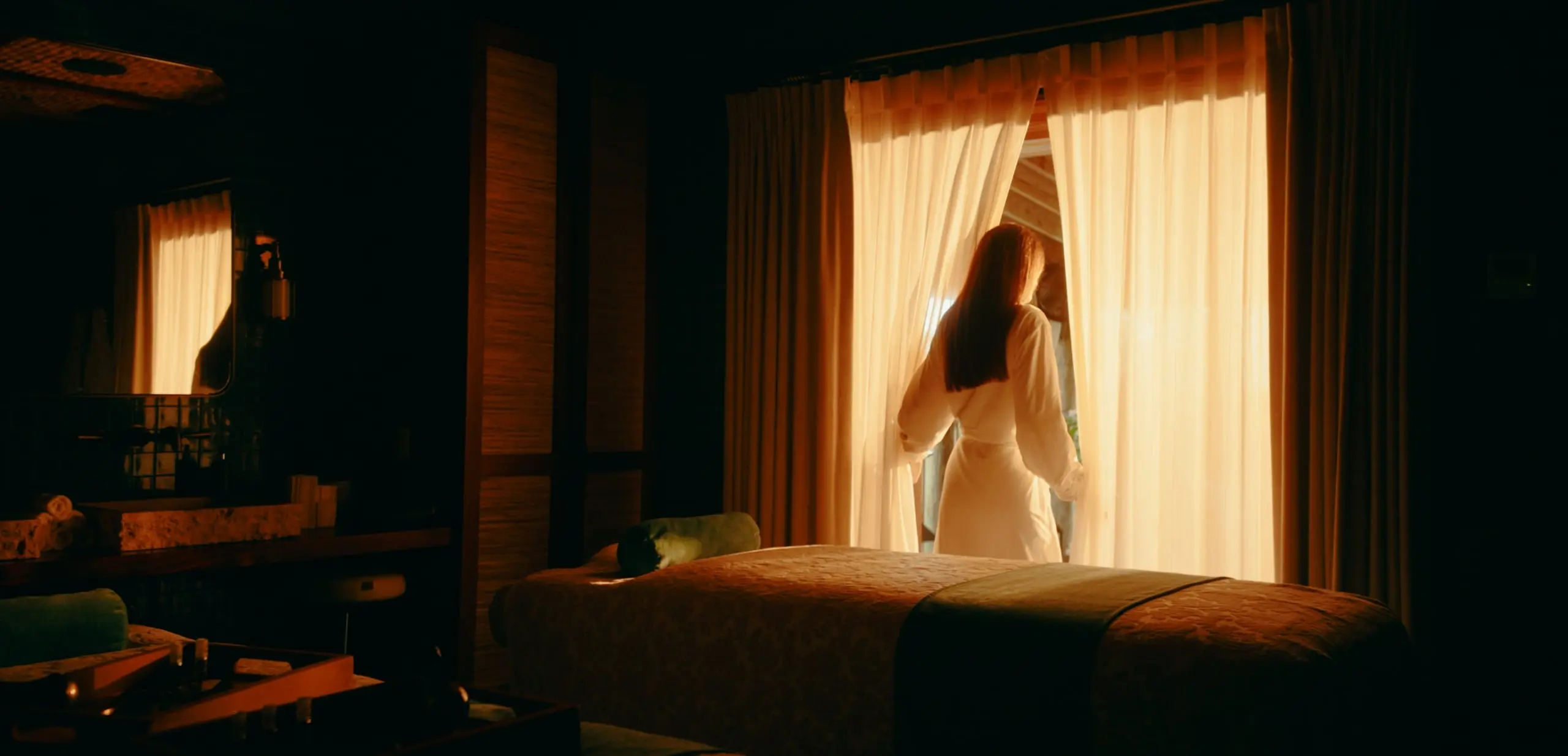A woman looking out through the curtains of her suite at Little Palm Island resort