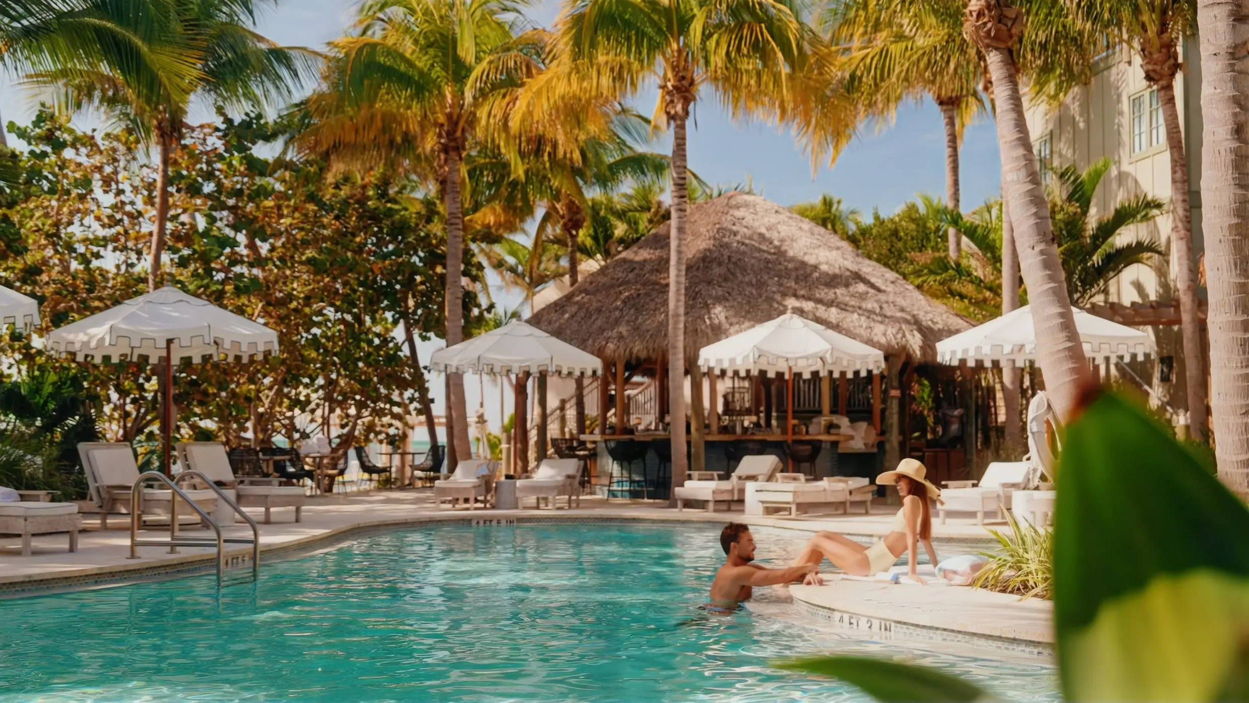 A couple relaxing by the lagoon style pool on Little Palm Island