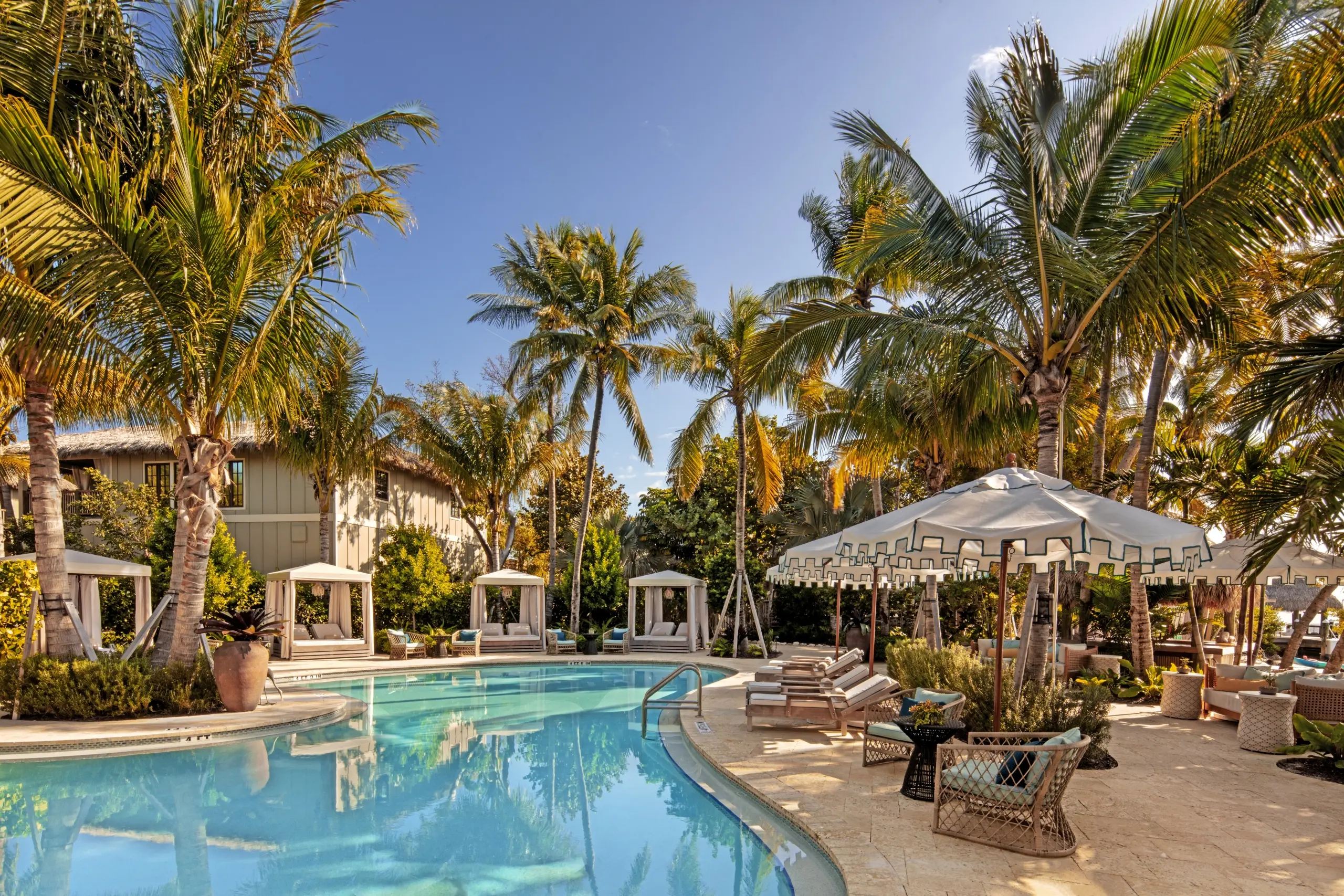 A lagoon style pool on Little Palm Island surrounded by palm tress and cabanas