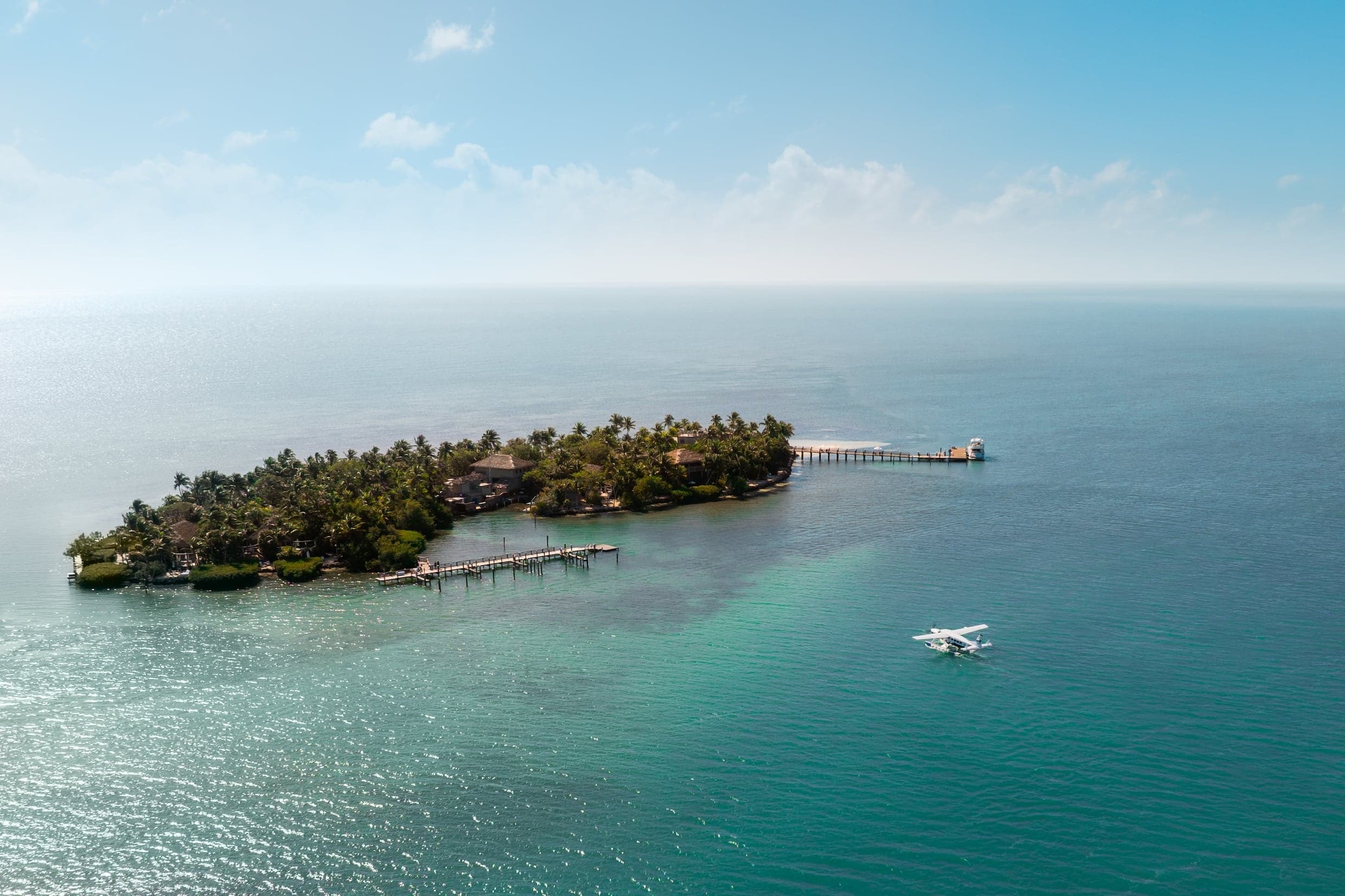 Aerial view of a seaplane arriving at Little Palm Island on a clear day. The water is crystal clear and green.